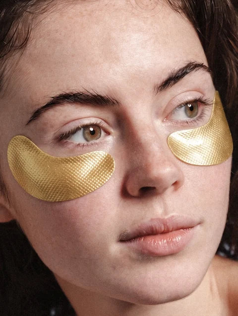 Woman wearing gold hydrogel under-eye patches to hydrate and refresh tired-looking eyes