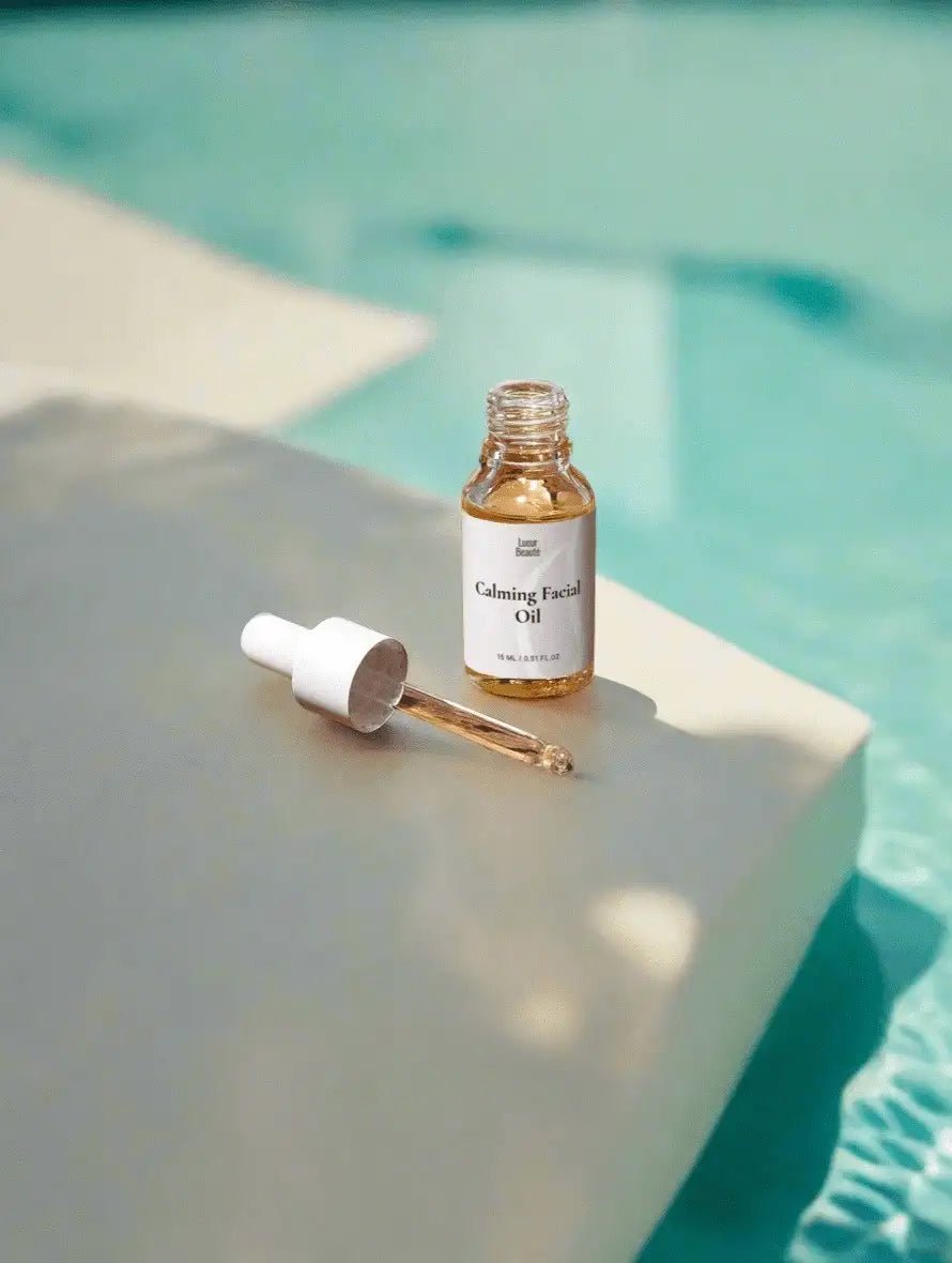 Calming facial oil bottle with dropper on a reflective surface near a pool