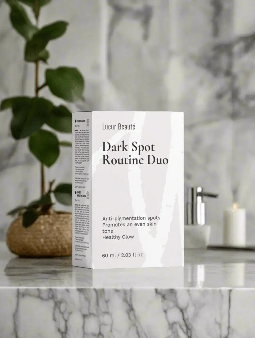 Dark Spot Routine Duo packaging on a marble surface with a plant and candle in the background