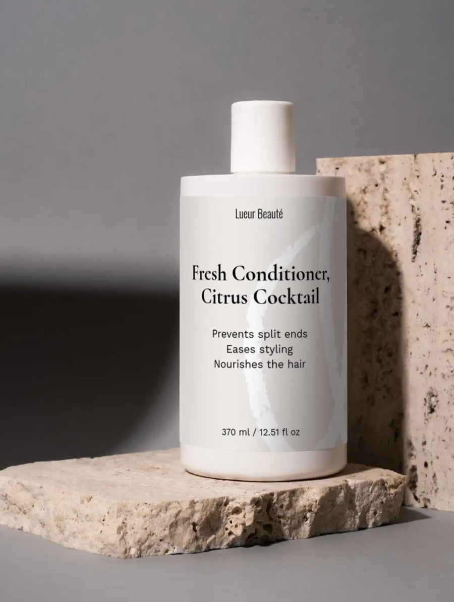 Lueur Beauté Fresh Conditioner Citrus Cocktail placed on textured stone slab with minimalist grey background