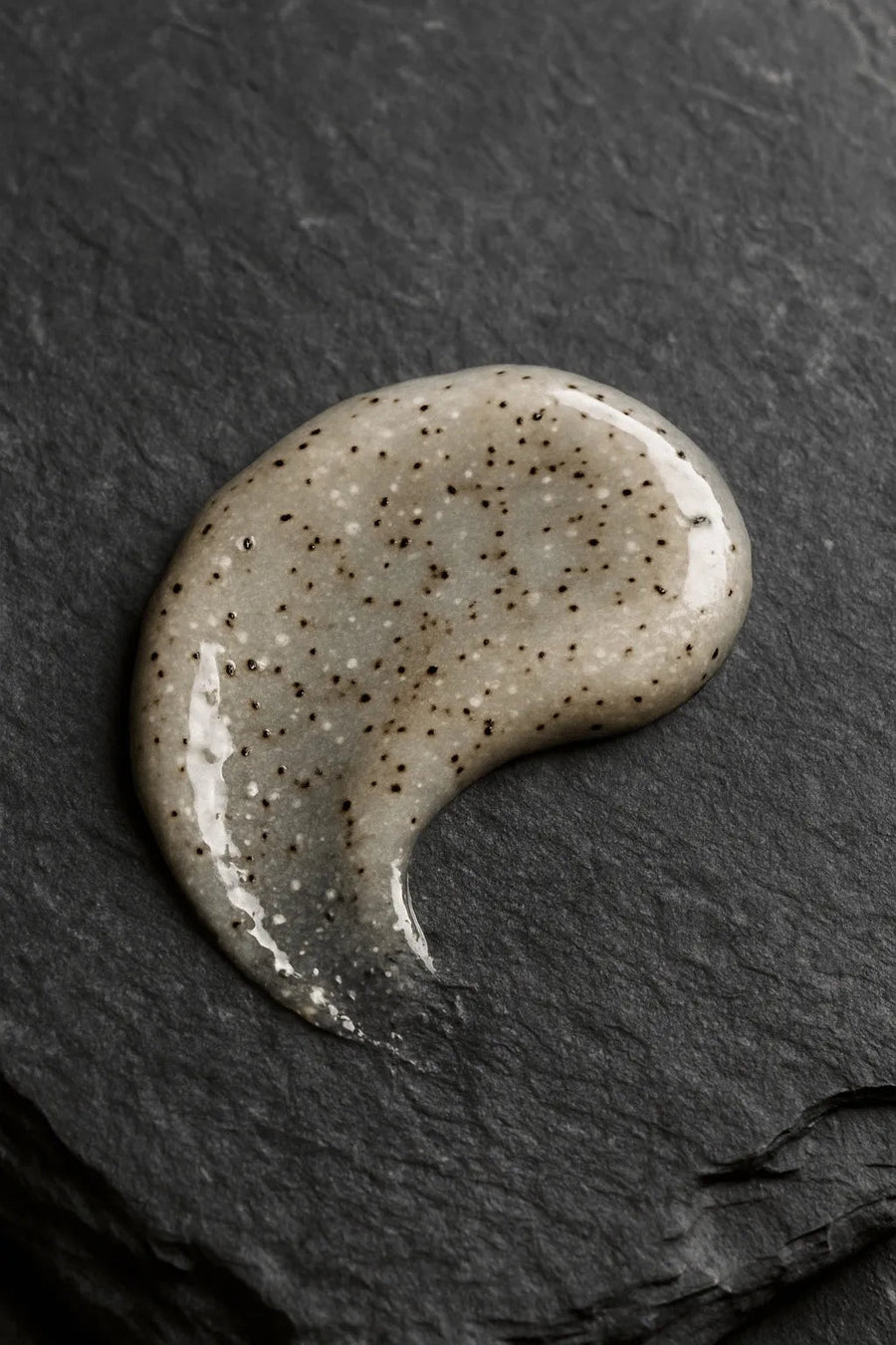 Texture of the Icelandic Volcano Face & Body Scrub with volcanic sand, shown on a dark stone surface.