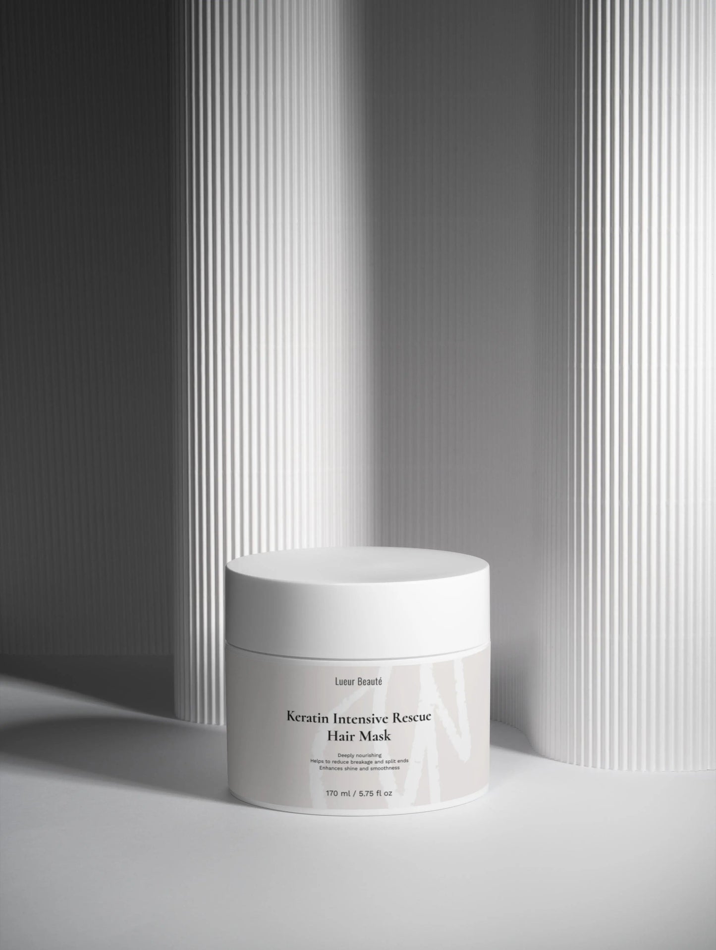 Lueur Beauté Keratin Intensive Rescue Hair Mask jar with minimalist grey striped background
