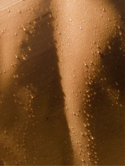 Close-up of wet skin with water droplets in warm golden light