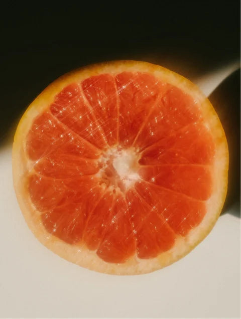 Close-up of a halved pink grapefruit on a light surface