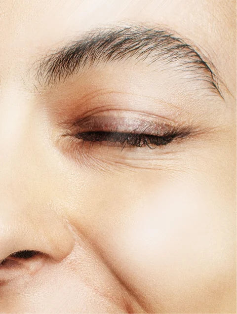 Close-up of a face showing a closed eye, eyebrow, cheek and part of the nose.