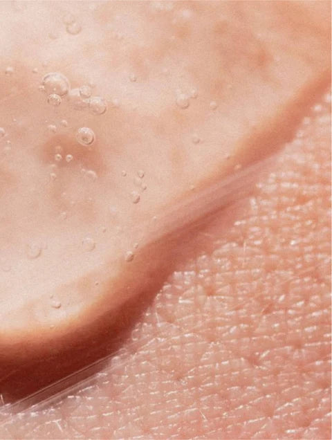 Macro view of transparent gel with small air bubbles spread over skin.