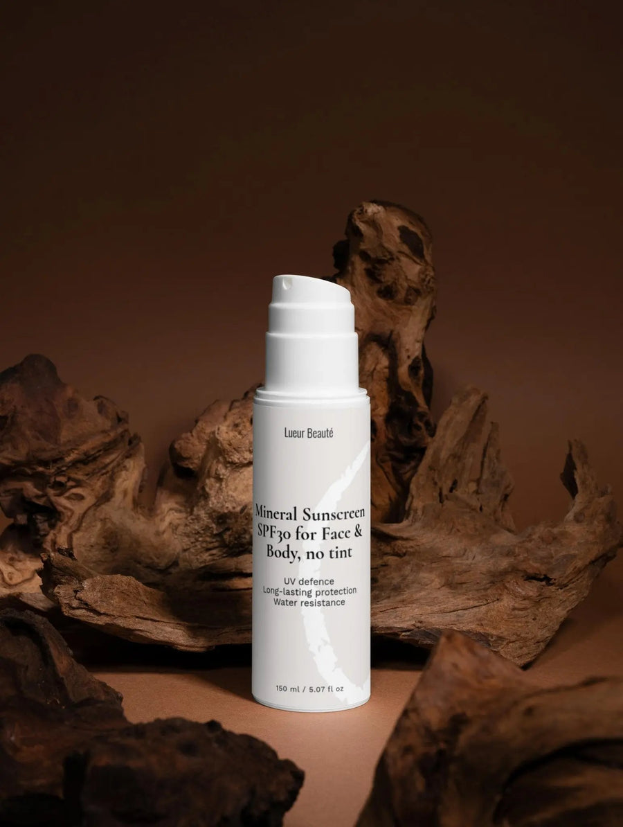 Lueur Beauté Mineral Sunscreen SPF30 bottle standing in a studio setting with natural wood textures in the background.