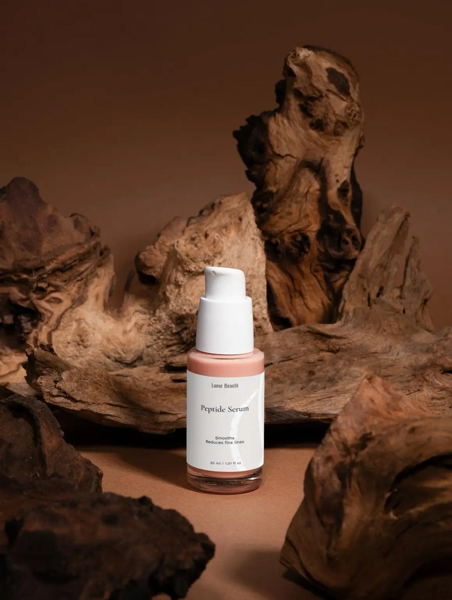 Skincare serum bottle labeled 'Peptide Serum' on a brown background with natural wood elements.