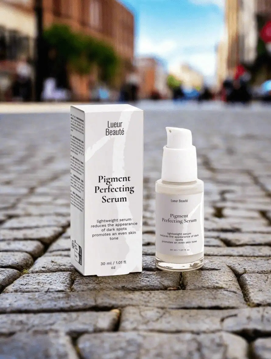 Pigment Perfecting Serum packaging and bottle on a stone pavement with blurred city background